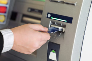 male hand businessman inserts credit card into the ATM